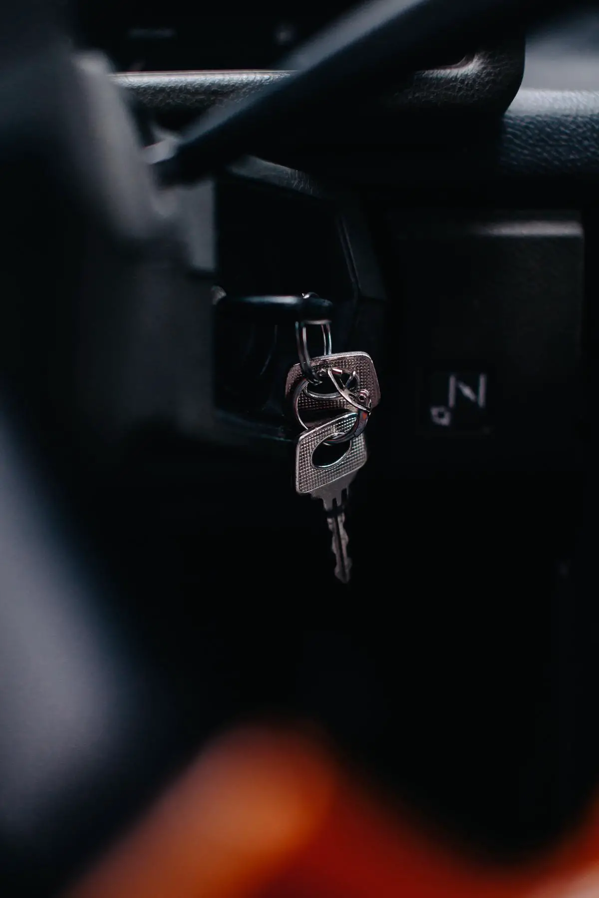 An image of a person holding car keys and looking at a car engine, representing the common car issues being described